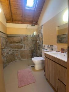 a bathroom with a toilet sink and a stone wall at Nascente, place in nature next to a waterfall in Loureiro
