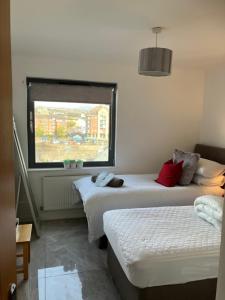 two beds in a room with a window at SWANSEA BAY, MARINA & ARENA VIEW Mins to BEACH & CITY in Swansea