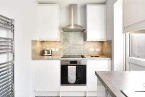 eine Küche mit weißen Schränken und einem Herd in der Unterkunft Elegant 2BR Aylesbury Home, Sleeps 4, Parking, Work, Leisure, Friendly in Buckinghamshire