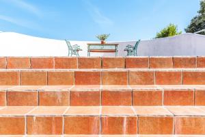 a brick wall with a table and benches on it at Sirens Villas - Sea View Private Pool Villas in Skopelos Town