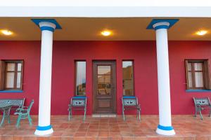 a red building with white columns and a door at Sirens Villas in Skopelos Town