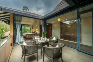 a patio with a table and chairs on a balcony at SaffronStays The Glass Grove in Panchgani