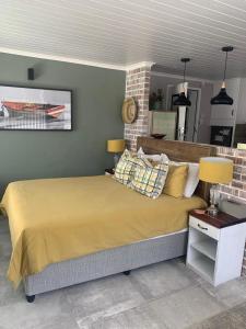 a bedroom with a large bed with yellow sheets and lamps at Just Chill Betty's Bay in Bettyʼs Bay