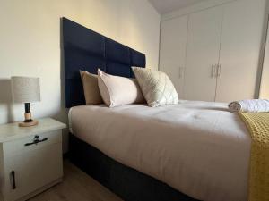a bedroom with a large bed with a blue headboard at Modern Downtown Escape in Gaborone