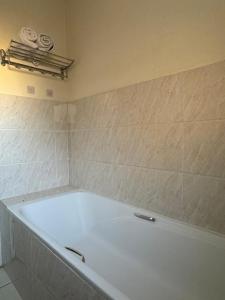 a bath tub in a bathroom with a tile wall at Modern Downtown Escape in Gaborone +5 photos