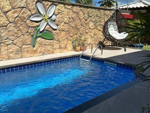 a swimming pool in front of a stone wall at Flor de Limão Hotel Boutique in Coroa Vermelha