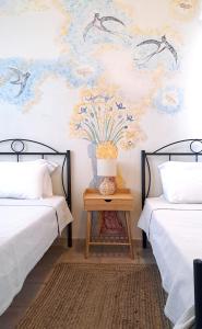a bedroom with two beds and a vase on a table at Sirens Villas in Skopelos Town