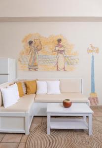 a living room with a white couch and a painting at Sirens Villas in Skopelos Town