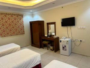 Cette chambre comprend deux lits, un bureau et une télévision. dans l'établissement فندق درة المنابر الفندقية, à Médine