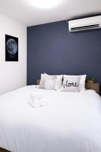 a bedroom with a white bed with a blue wall at The Peak Tsutenkaku in Osaka