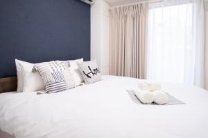a bedroom with a white bed with pillows and a window at The Peak Tsutenkaku in Osaka