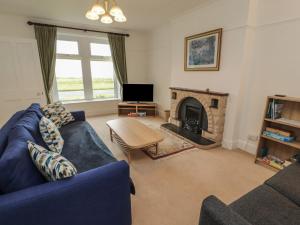a living room with a blue couch and a fireplace at Burnbank in Maryport