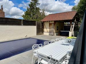 a white table and chairs next to a swimming pool at La villa d'exception Piscine Jacuzzi Sauna Hammam in Landen