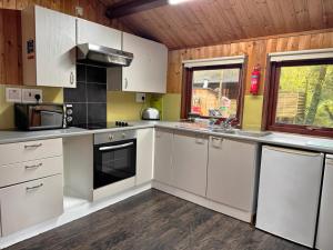 a kitchen with white cabinets and a stove top oven at Snowdrop 14 Hot tub-Woodlandlodges-Tenby-Pendine in Carmarthen +3 photos