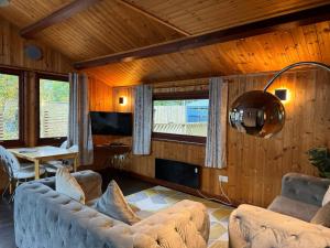 a living room with a couch and a table at Snowdrop 14 Hot tub-Woodlandlodges-Tenby-Pendine in Carmarthen