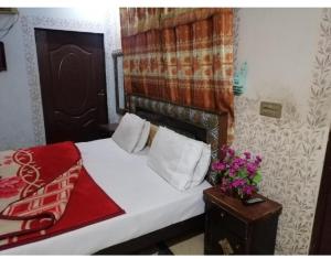 a bedroom with a bed and a table with flowers on it at New Faizan Hotel in Lahore