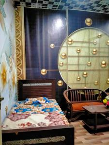 a bedroom with a bed and a chair and a table at New Faizan Hotel in Lahore