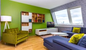 a living room with a blue couch and a green wall at Abieshomes Serviced Apartments - Votivpark in Vienna