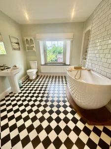 ein Badezimmer mit großer Badewanne und Waschbecken in der Unterkunft The old Manor House in Lifton