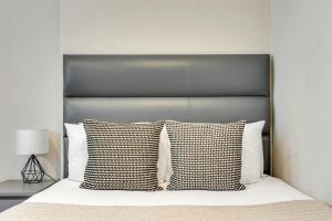 a bed with a black headboard and two pillows at Cleveland Residences Chelsea in London
