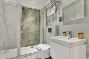 a white bathroom with a shower and a sink at Cleveland Residences Chelsea in London