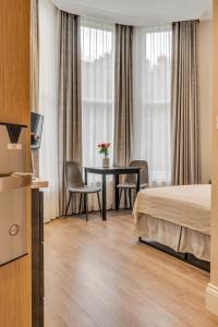 a hotel room with a bed and a table and chairs at Cleveland Residences Chelsea in London