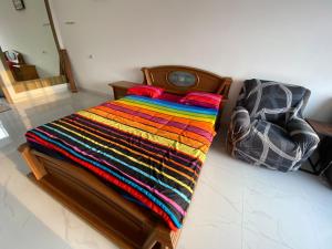 a bed with a colorful blanket and a clock on it at Kamar no 4 in Sampal 2