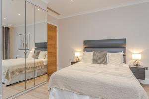 a bedroom with two beds and a mirror at Cleveland Residences Chelsea in London