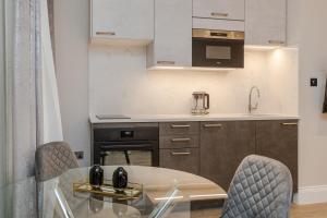 a kitchen with a glass table and chairs at Cleveland Residences Chelsea in London