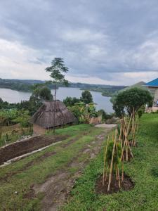 a field with a view of a river and a hut at sakalaka in Fort Portal