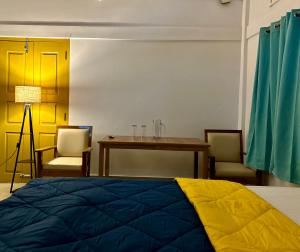 SibsāgarParag Abode - A Luxury Homestay的一间卧室，配有一张床、一张桌子和几把椅子
