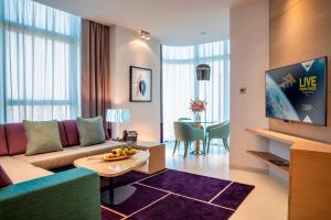 a living room with a couch and a tv at Capital Centre Arjaan by Rotana in Abu Dhabi