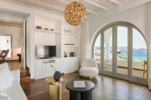 a living room with a couch and a tv at Grace Mykonos in Agios Stefanos