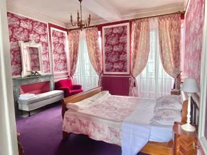 a bedroom with pink walls and a bed and a couch at L'Hotel de Hercé Chambre d'Hote in Mayenne