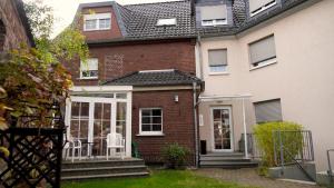 a brick house with a porch and white chairs at Hotel Am Weyerhof in Kerpen
