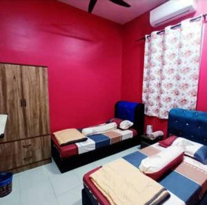 a room with two beds and a red wall at Homestay Raikan Cinta in Malacca +7 photos