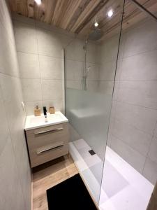 Un baño blanco con ducha y lavabo. en La Lézardière - Chalet spacieux près des pistes, en La Toussuire