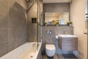 a bathroom with a tub and a toilet and a sink at Apartment 2 Jester Court in Windermere
