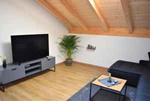 a living room with a black couch and a flat screen tv at Ferienwohnungen Rosenheim - Pang in Rosenheim