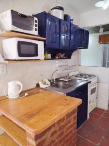 a kitchen with blue cabinets and a sink and a microwave at Casita del Mar in Las Toninas