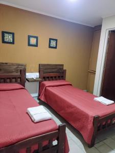 two beds in a room with red sheets at Hotel Parque in Villa Mercedes