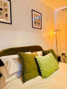 a bed with green and white pillows on it at The Secret Garden Retreat With Hot Tub in Manchester