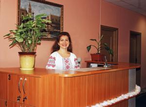 a woman standing behind a counter with a potted plant at Mini-hotel on Elektrotechnichnaya Street 18 in Kyiv