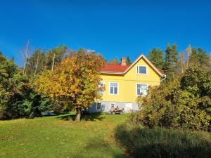 a yellow house with a red roof in a field at Villa and cottage by the sea in Sunnanberg