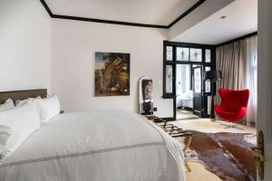 a bedroom with a large bed and a red chair at Le Manoir Boutique Estate in Johannesburg