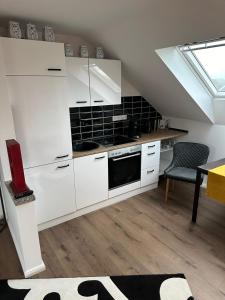 a kitchen with white cabinets and a black tile wall at Ferienwohnung Gütersloh in Gütersloh