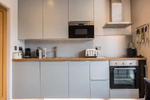 a kitchen with white cabinets and a stove top oven at Apartment 2 Jester Court in Windermere