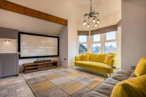 a living room with a yellow couch and a flat screen tv at Apartment 3 Jester Court in Windermere