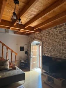 a living room with a stone wall and a flat screen tv at Vila, Upper Qeparo in Qeparoi i Sipërm