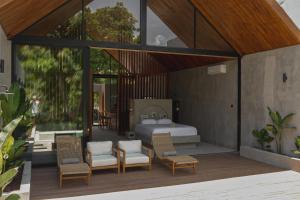 ein Schlafzimmer mit einem Bett und Stühlen auf einer Terrasse in der Unterkunft Karang Villas Uluwatu in Uluwatu
